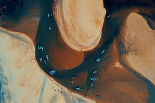 A stunning aerial view of boats navigating around sandy formations in Kemasik, Malaysia at low tide.
