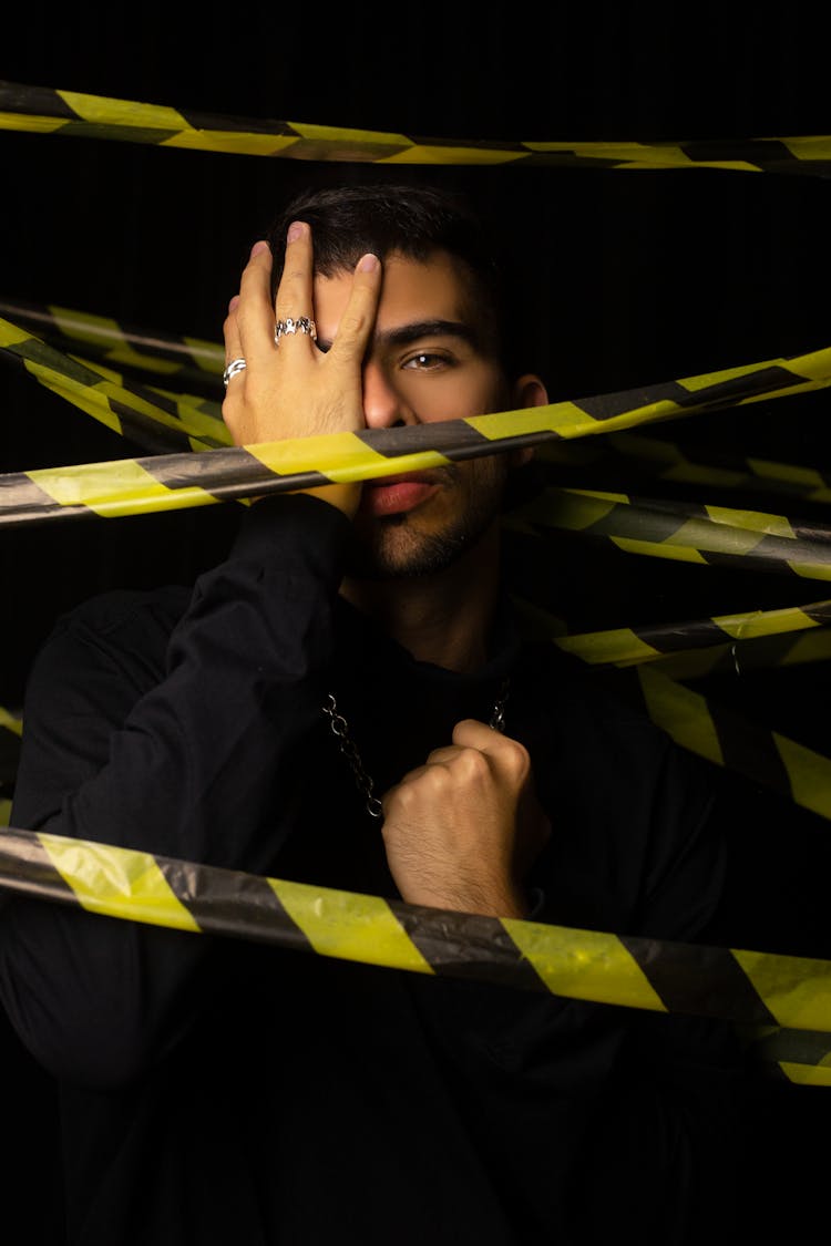 Man Holding His Face While Surrounded With Caution Tape