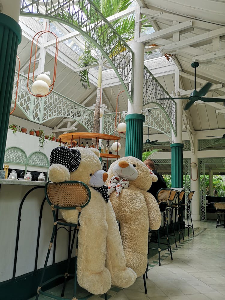 Large Teddy Bears On Chairs At A Bar