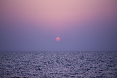 Free Tranquil ocean scene during twilight with a vibrant sunset horizon. Stock Photo
