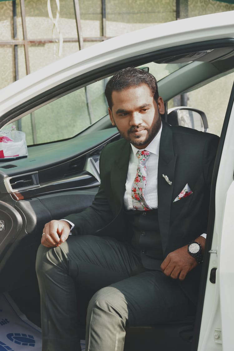 A Man In A Suit Sitting In A Car