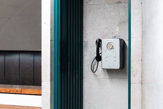 A classic rotary phone is mounted on a wall inside a modern building.