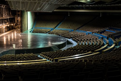 Free A large, empty auditorium with a circular stage and retro seating design. Stock Photo