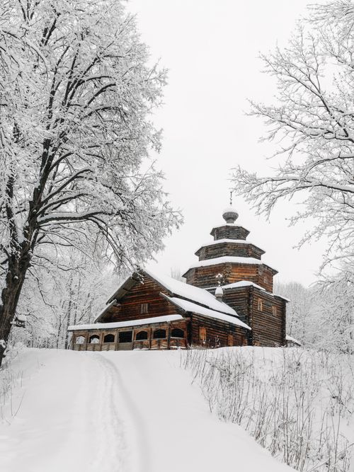 Free Snow-laden trees frame a historic wooden church in Russian winter scenic view. Stock Photo