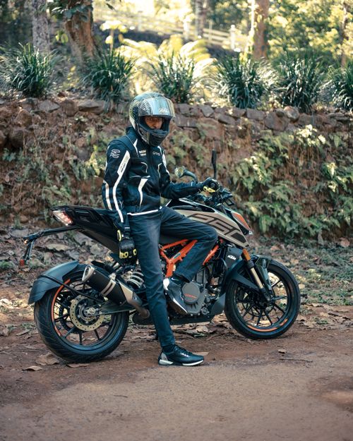 Free A motorcyclist poses with a bike in a natural setting wearing a helmet and jacket. Stock Photo