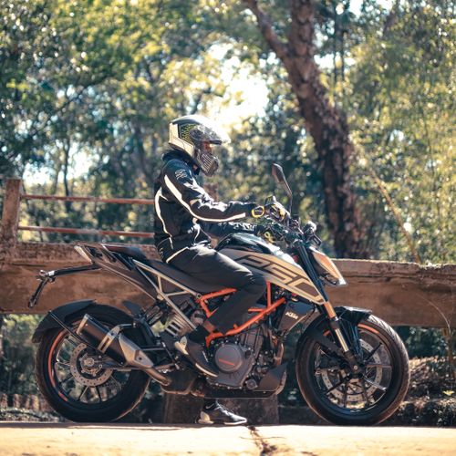 Free A motorcyclist in full gear rides through a scenic forest area, showcasing the thrill of outdoor adventures. Stock Photo