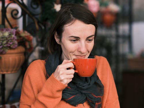 
A Woman in a Sweater Having Coffee