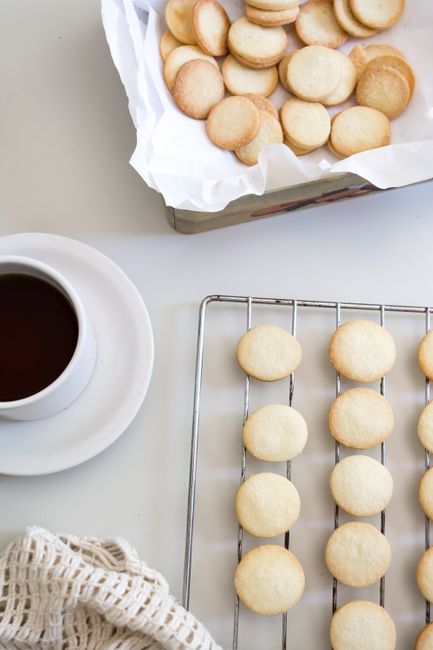Freshly baked butter cookies on cooling rack, paired with a cup of black coffee.