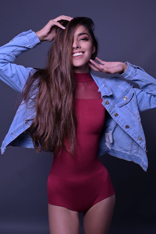 
A Woman Wearing a Denim Jacket over a Red Turtleneck Bodysuit