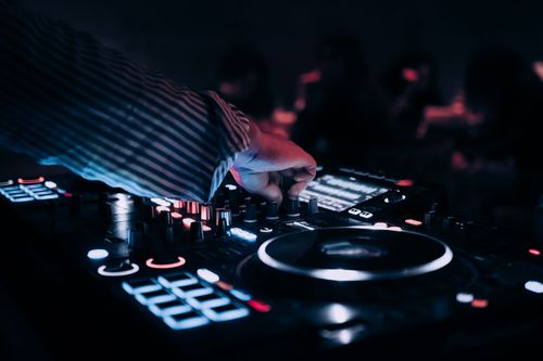 Free Close-up of DJ mixing music on an illuminated console at a nightclub. Stock Photo