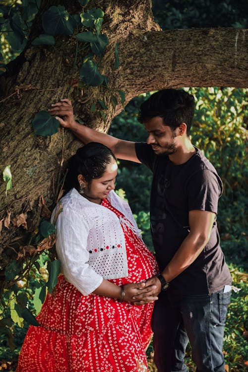 Man with his Pregnant Wife Standing under Tree