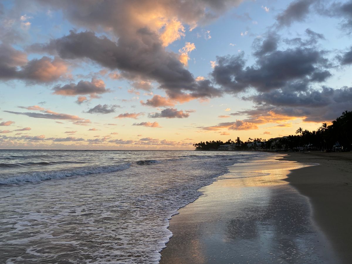 Serene sunset over Cabarete Beach with waves gently lapping the shore under a cl