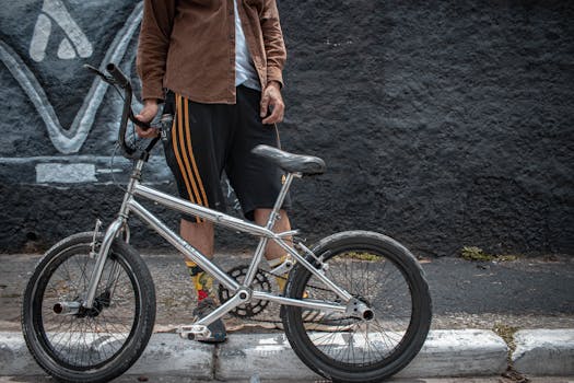 A young man in casual attire stands with his BMX bike against a graffiti wall.