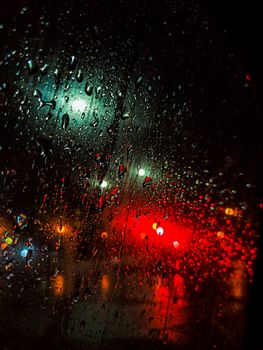 Raindrops on a window with blurred city lights creating a moody and vibrant atmosphere.