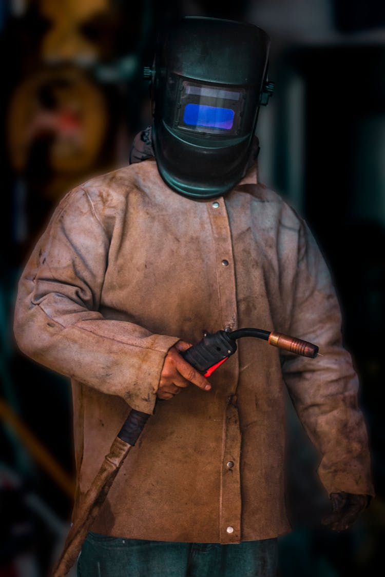 A Man Wearing A Dirty Suit And A Welder Mask