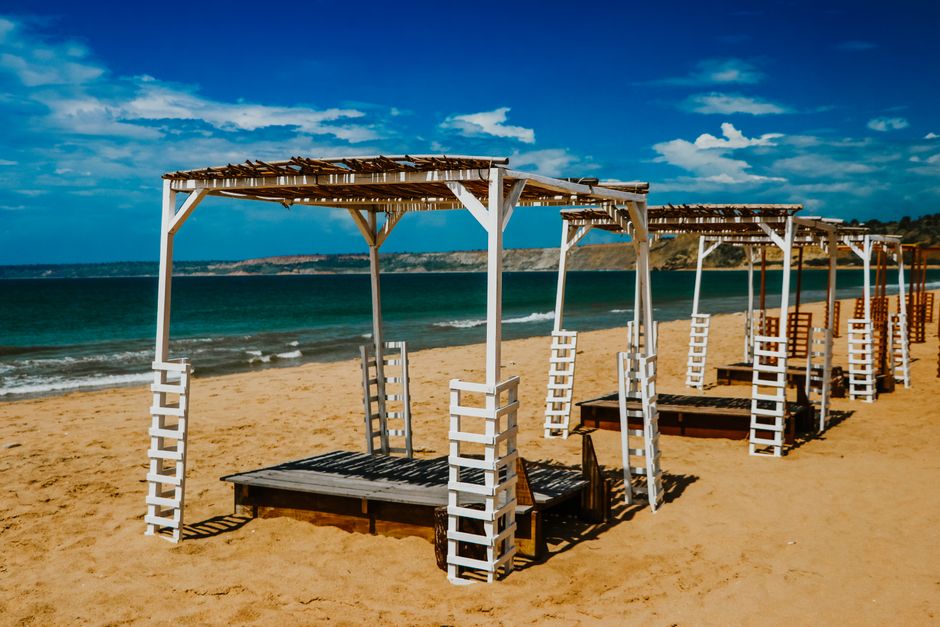 Relaxing beach scene with wooden canopies, perfect for summer leisure and vacation vibes.