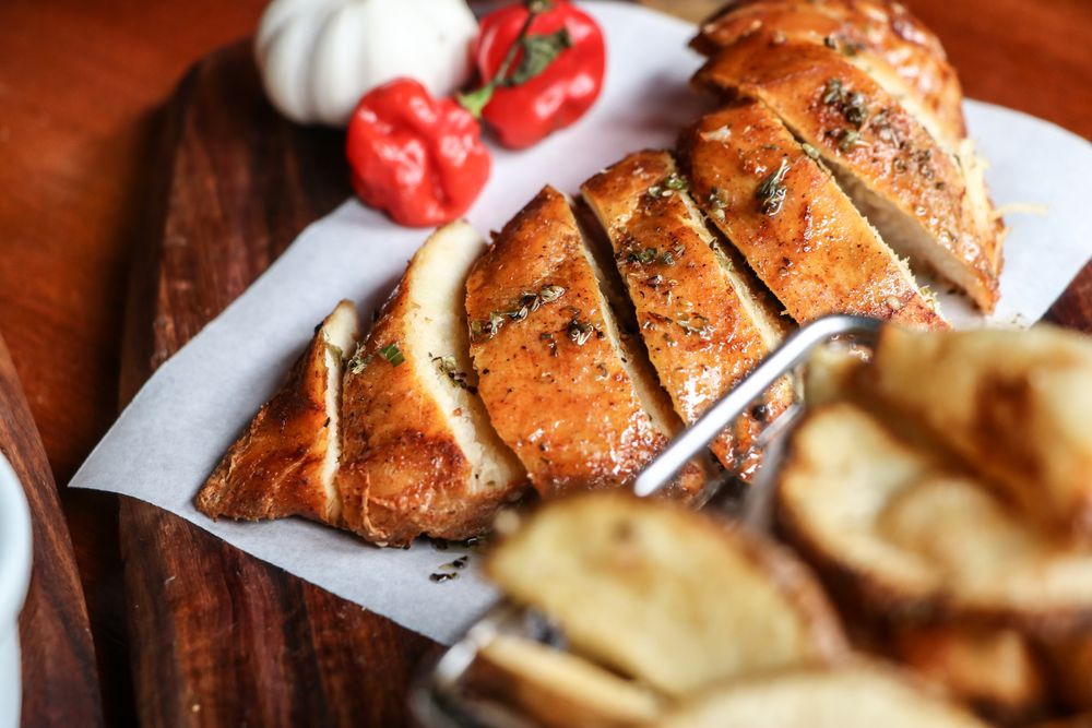 pellet grill chicken breast — sliced against the grain on a wooden board with fresh herbs