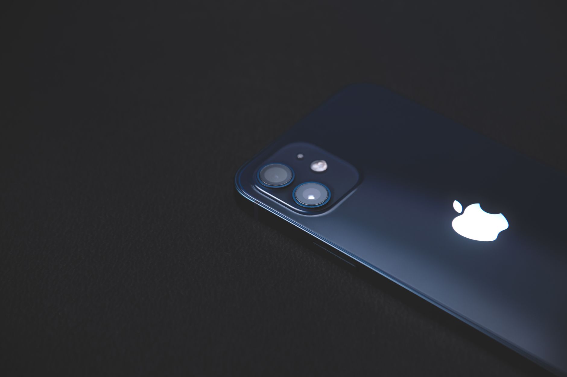 Close-up of a modern smartphone on a dark textured surface, highlighting its sleek design.