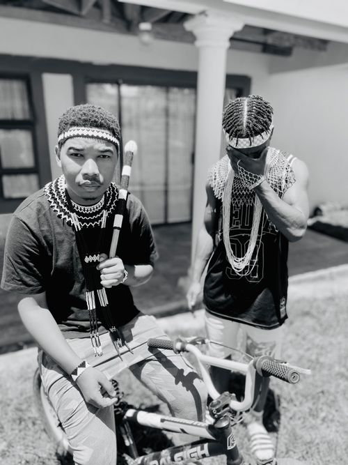 Free Two young men in traditional attire with a bicycle, captured in black and white in Bizana, South Africa. Stock Photo