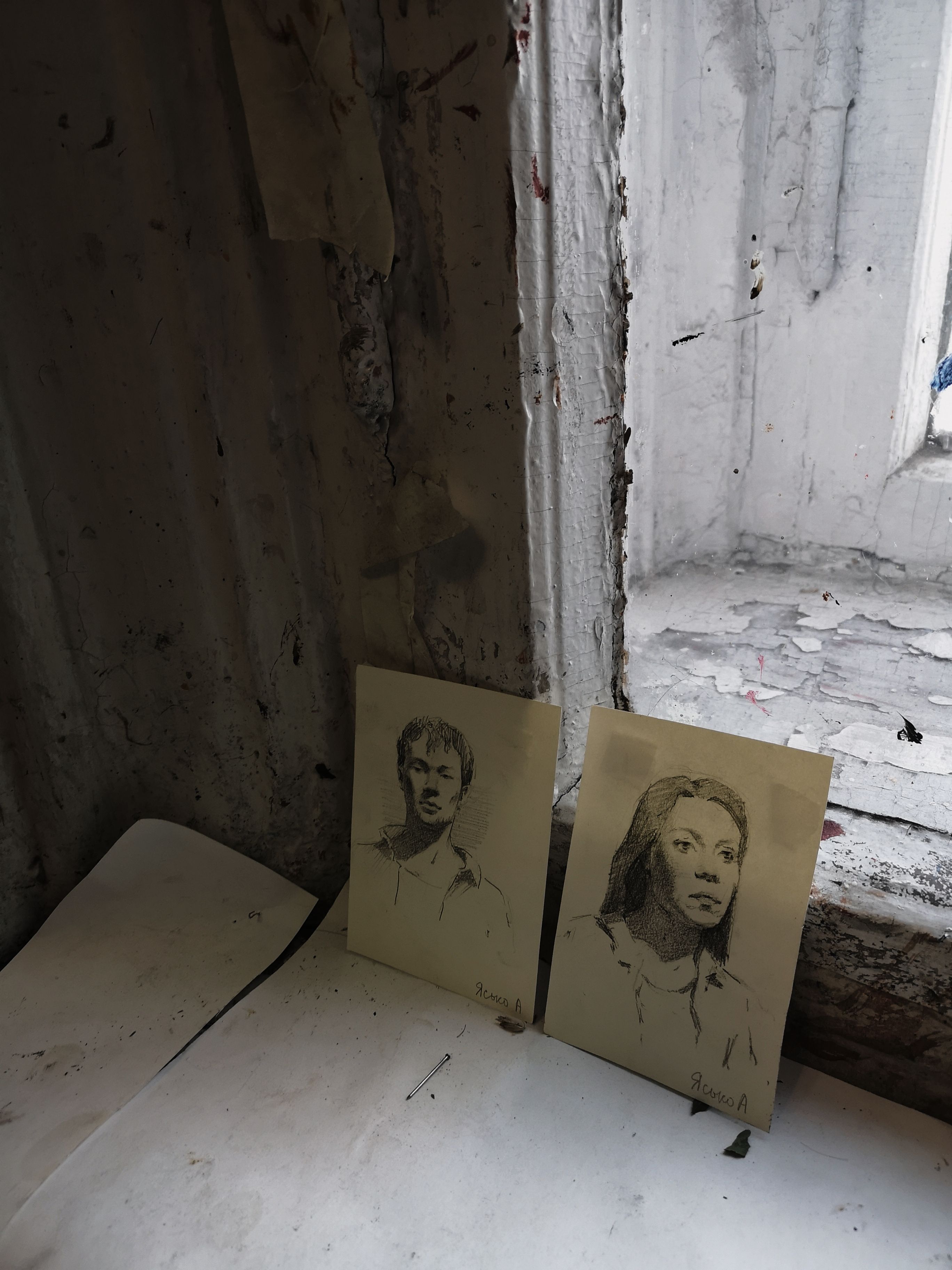Charcoal sketches of a man and a woman leaning against an old window wall.