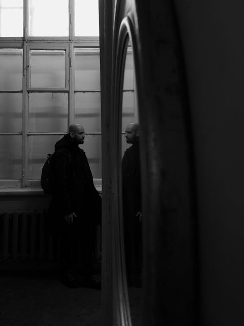 Free 
A Grayscale of a Man by the Window Stock Photo