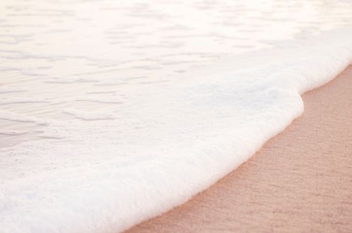 Free A tranquil beach scene with gentle waves washing over the sandy shore. Perfect for relaxation themes. Stock Photo