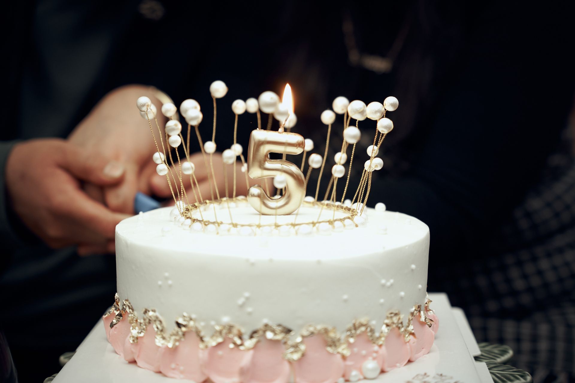 A beautifully decorated cake with a golden number five candle lit on top, perfect for a fifth birthday celebration.