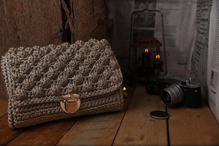 Close-Up Photo Of A Knitted Bag Near A Camera