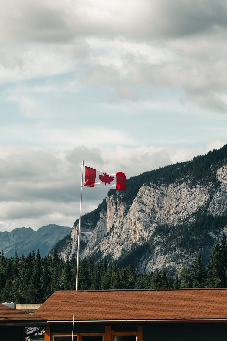 Flag Of Canada On Pole With View Of Mountain On Background