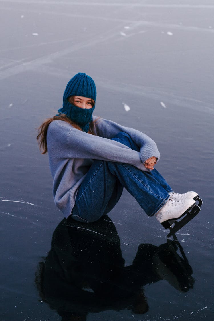 Woman With Ice Skates Sitting On Ice