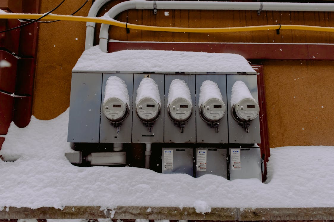 Free A row of electric meters covered in snow during winter, illustrating infrastructure resilience. Stock Photo