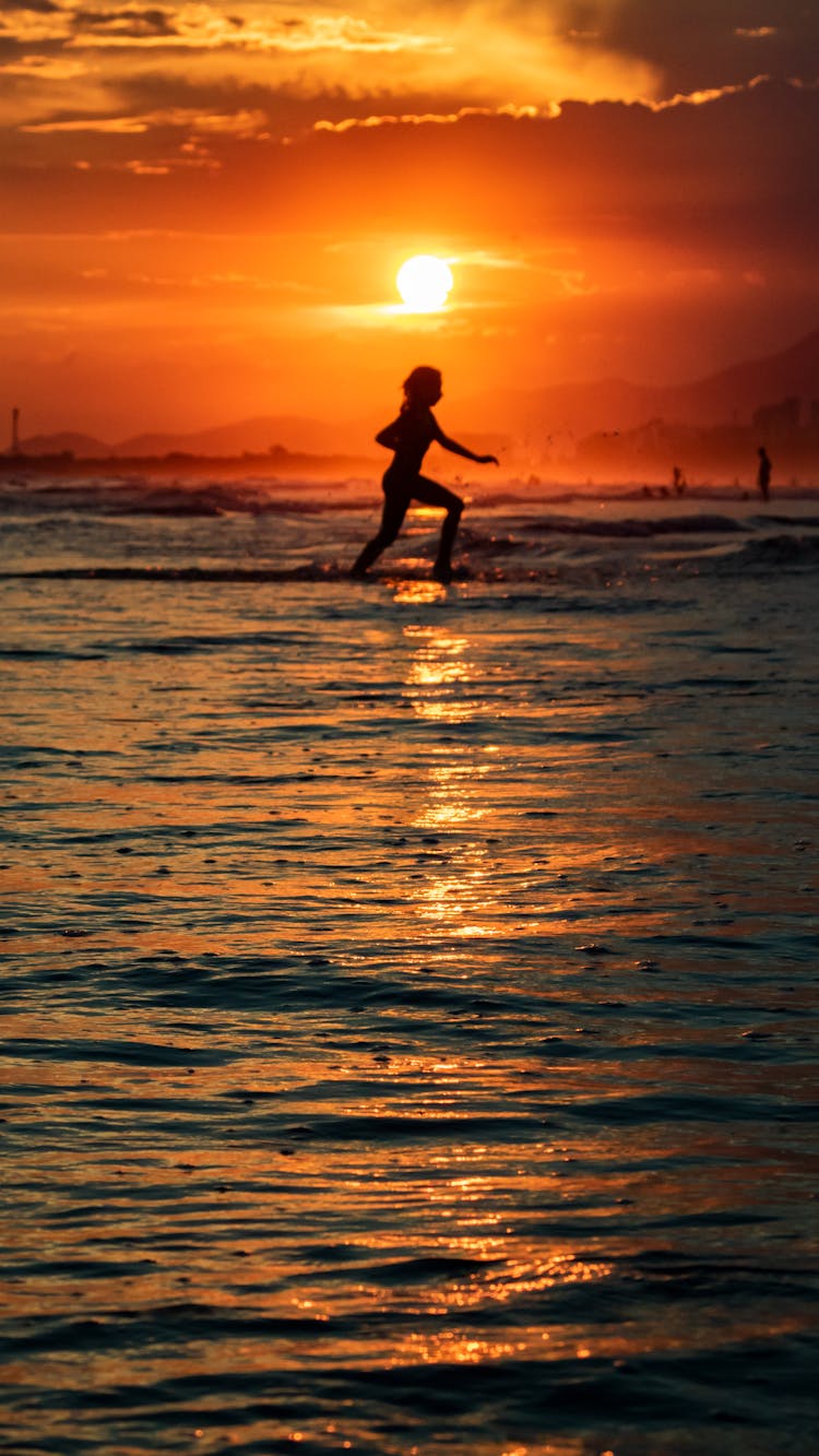 Silhouette Of A Person Running At The Beach