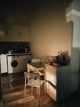 Warm sunlight illuminates a small kitchen in a Budapest apartment, capturing a cozy atmosphere.