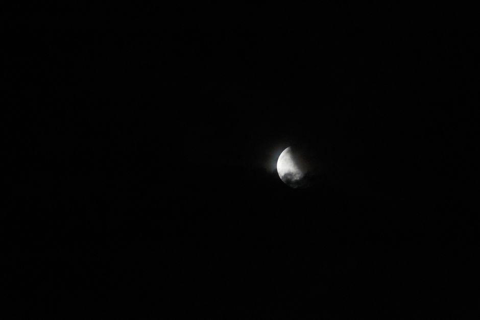 Fotomural Una impresionante vista de la luna creciente rodeada de oscuridad, capturada en un cielo nocturno.