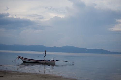 Brown Boat on Sea Under White Clouds
