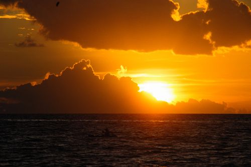 Free Beautiful sunset over the ocean with dramatic golden clouds and silhouettes. Stock Photo