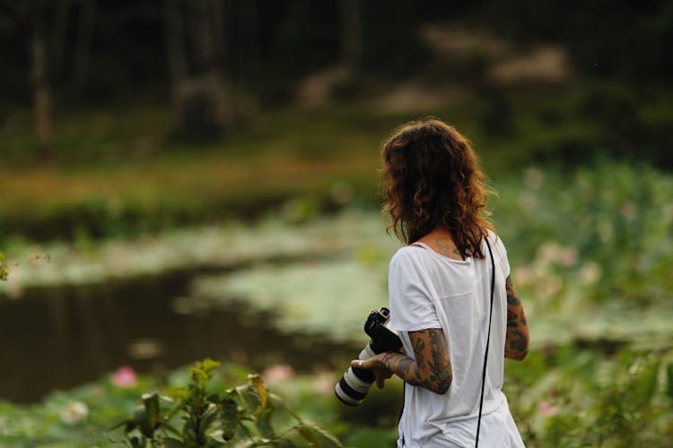 Woman In White Shirt Holding A Professional Camera