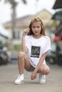 Woman in White Crew Neck T-shirt Sitting on Brown Wooden Bench
