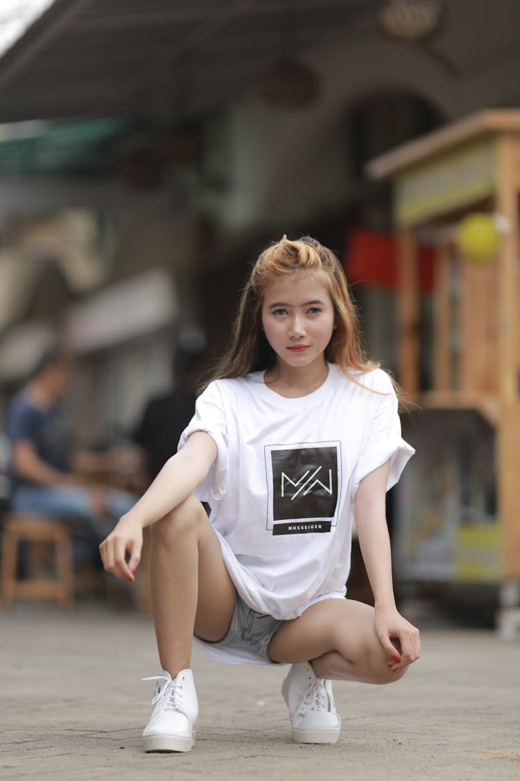 Woman Wearing A White Shirt Squatting On The Street