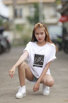 Stylish young woman in casual wear, squatting for a modern urban photo shoot.