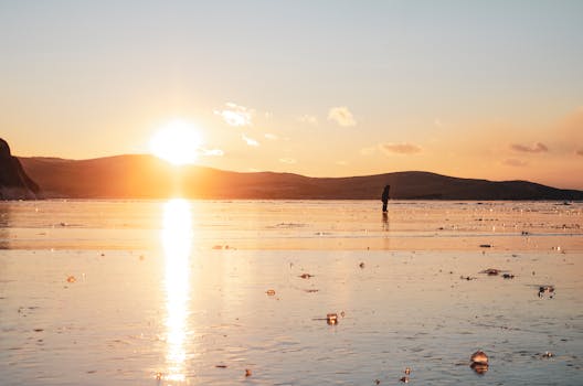 A serene sunrise with a person on a tranquil beach, perfect for reflecting nature's beauty.