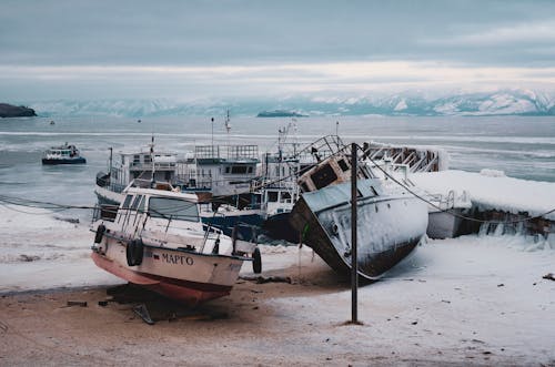 Rusty Boats Abandoned on Snowy Beach