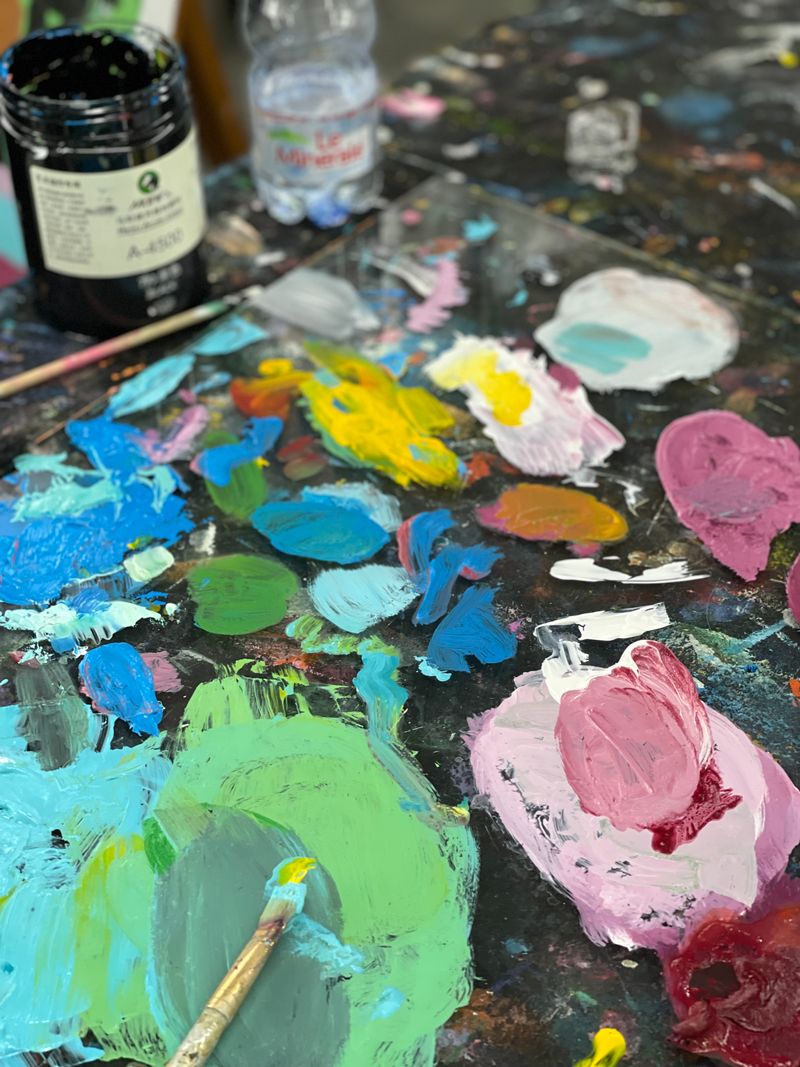 Paintbrush resting on artist palette with mixed colors