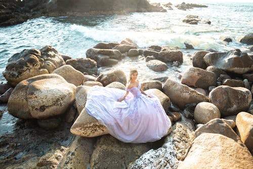 Free A Woman in a Princess Gown Sitting on Rocks Stock Photo