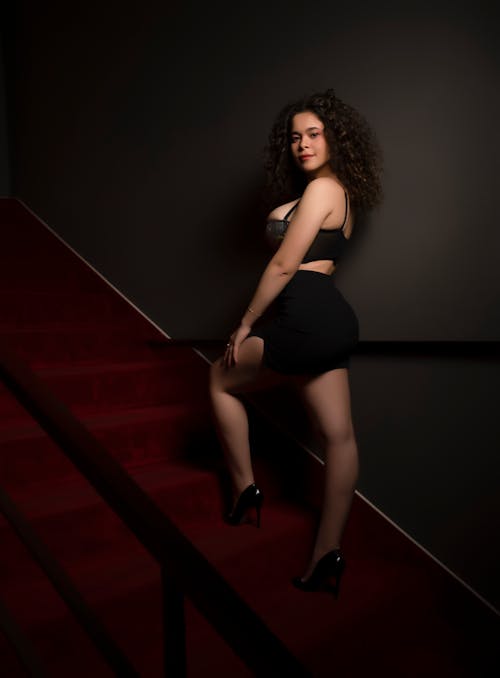 Free Woman in Black Clothes Posing on a Red Staircase Stock Photo