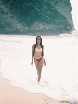 Captivating shot of a woman enjoying a tranquil walk on a Bali beach. Ideal for travel and lifestyle imagery.