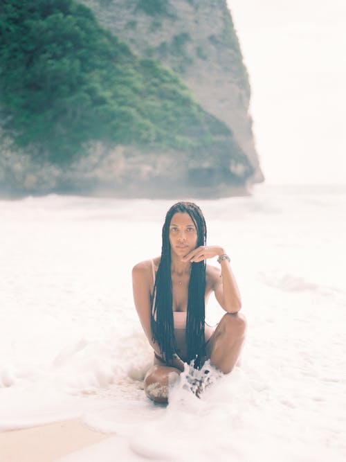 Free Braided Hair Woman Sitting on the Seashore  Stock Photo