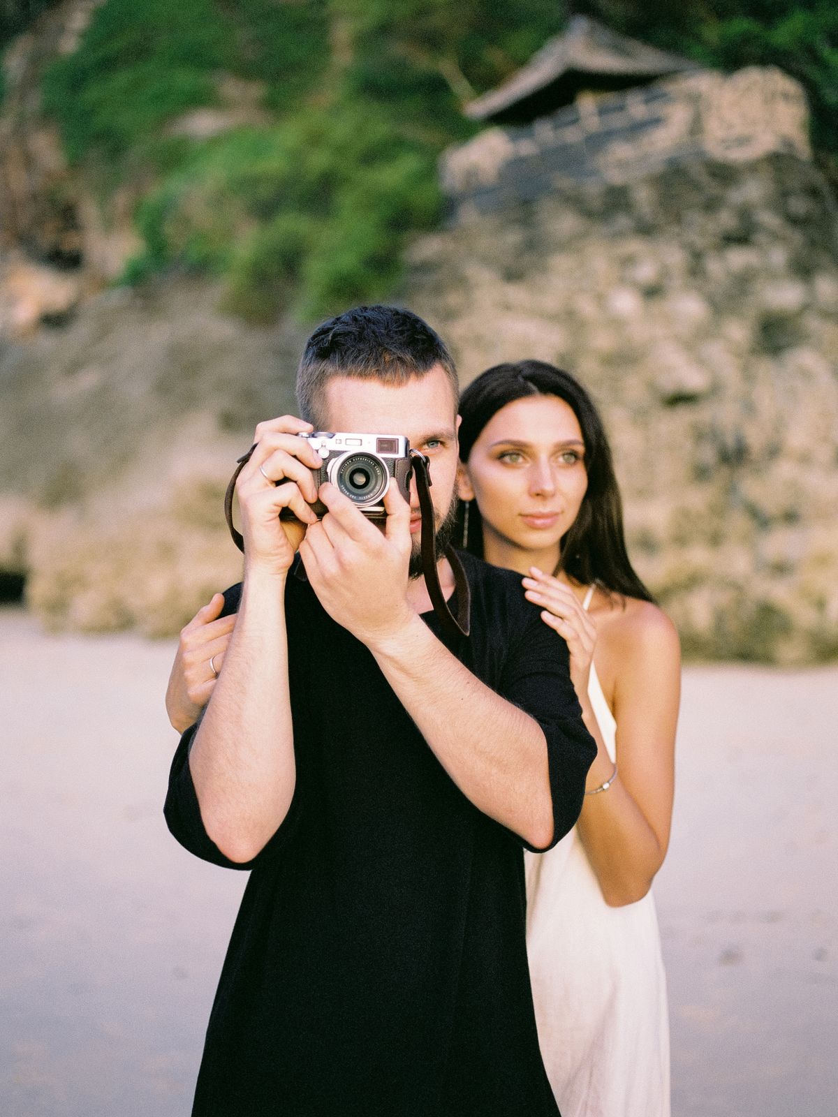 A couple on a Bali beach, one of them shooting with a compact camera