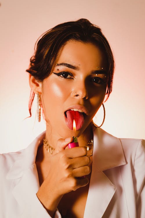 Attractive Woman with Strong Makeup and Piercing Pretending Licking Flame from Lighter