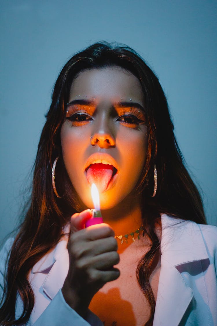 Young Woman Holding A Lighter And Sticking Her Tongue 